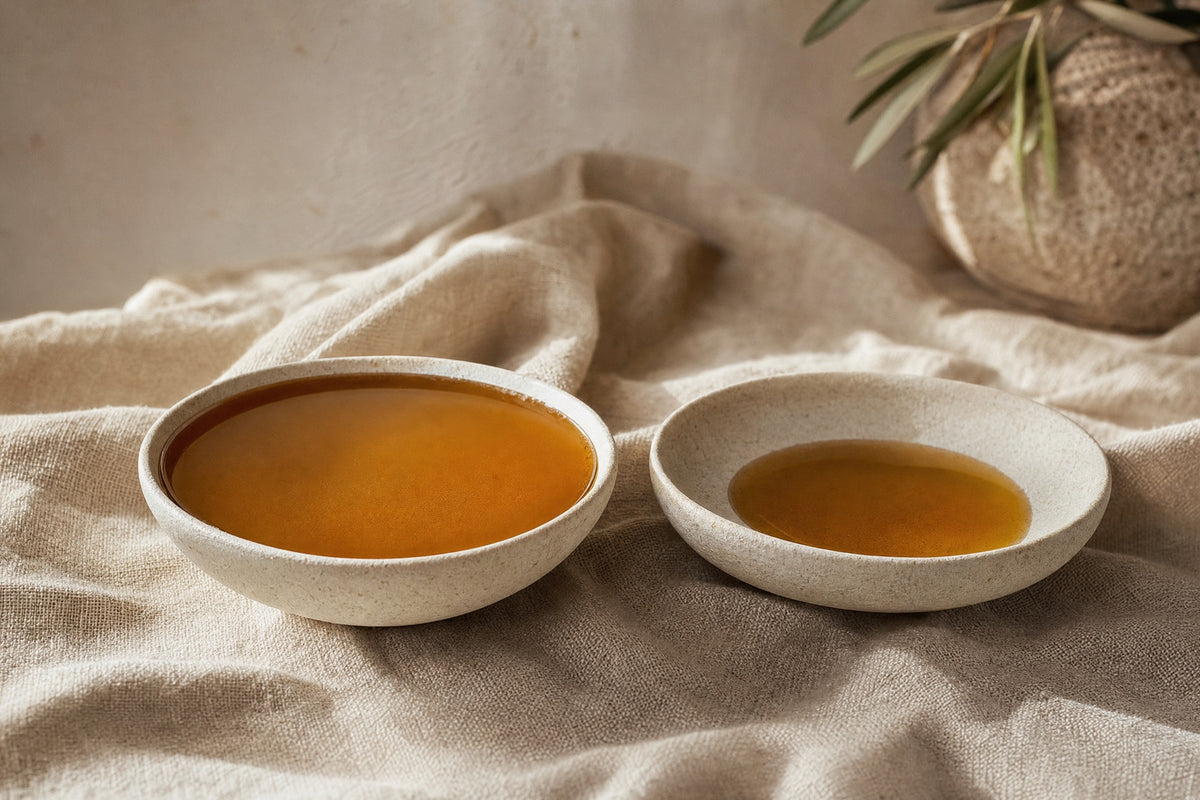 Two stone bowls on linen, one full of amber liquid and one a third full