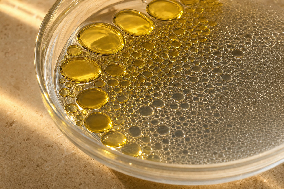 Oil beading on water in a glass bowl, large droplets breaking into many small ones