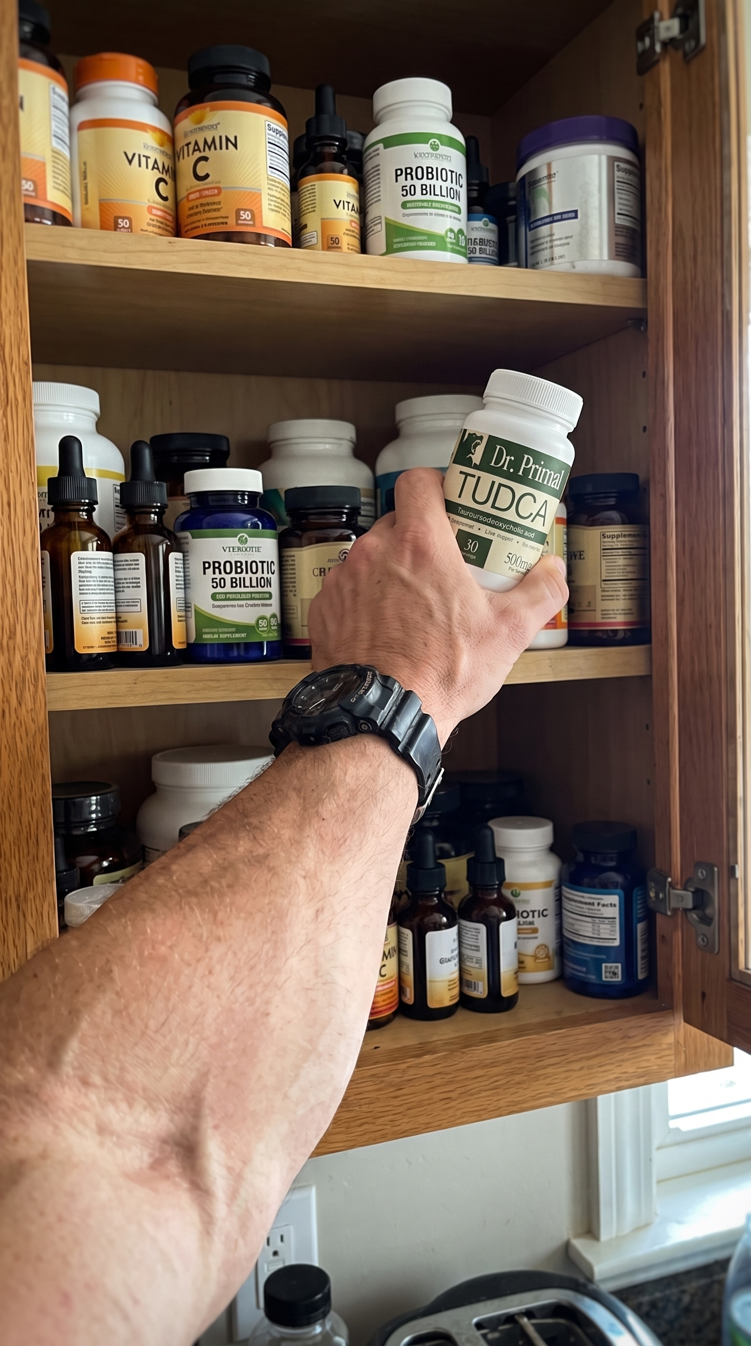 Hand reaching into a kitchen cupboard packed with half-used supplement tubs and bottles